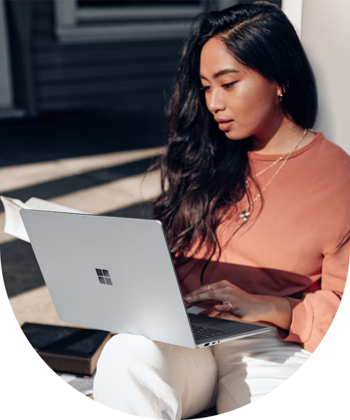 Kvinna håller i en öppen laptop, solljuset skiner på henne